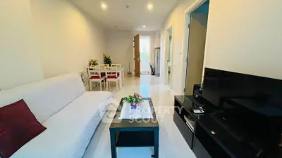 Modern living room with cozy sofa, TV, and dining area in open layout apartment.