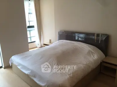 Cozy bedroom with large window and modern bed in a bright apartment.