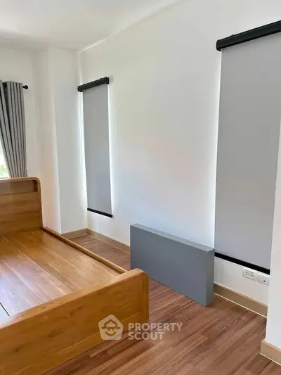 Spacious bedroom with wooden flooring and modern blinds, perfect for a cozy retreat.