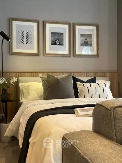 Elegant bedroom with stylish decor and cozy ambiance, featuring framed art and plush bedding.