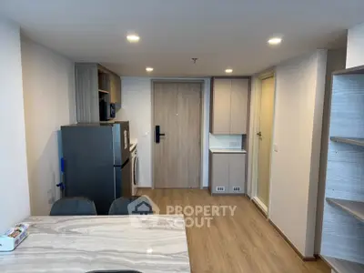 Modern apartment interior with open kitchen and dining area, featuring sleek wooden flooring and contemporary lighting.