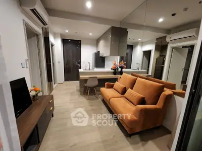 Modern living room with stylish orange sofa and open kitchen layout in a contemporary apartment.