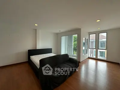 Spacious bedroom with large windows and wooden flooring in modern apartment