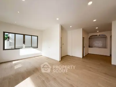 Spacious open-plan living area with wooden flooring and ample natural light.
