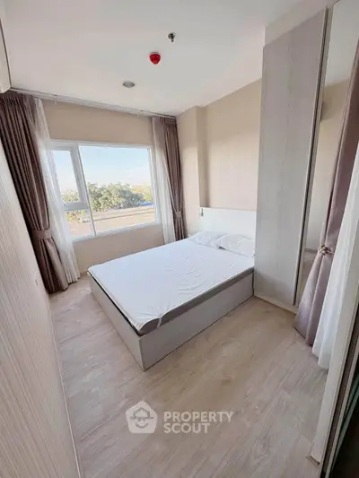 Modern bedroom with large window and natural light in a stylish apartment.