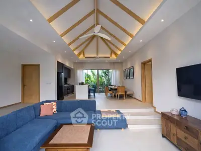 Spacious modern living room with vaulted ceiling and open layout, featuring a stylish blue sectional sofa and elegant decor.