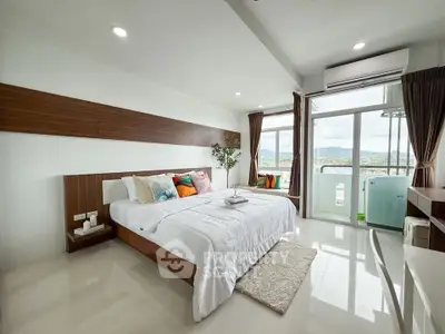 Spacious modern bedroom with large windows and scenic view, featuring elegant decor and natural light.