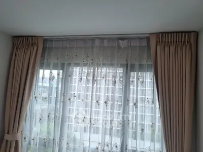 Elegant window with sheer curtains offering a city view in modern apartment.