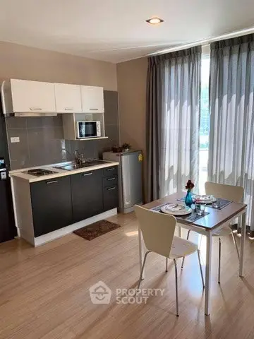 Modern kitchen with dining area and natural light, featuring sleek cabinetry and stylish decor.