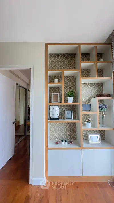 Stylish living room with elegant built-in shelving and decorative wallpaper accent.