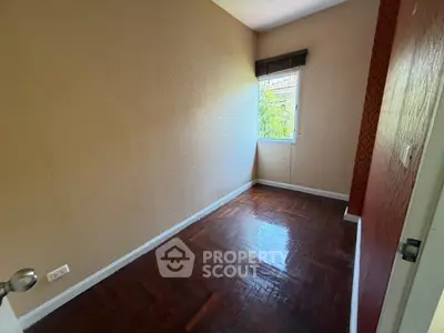 Cozy small bedroom with wooden flooring and natural light from window