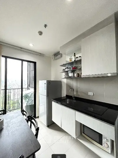 Modern kitchen with sleek cabinetry and city view from balcony.