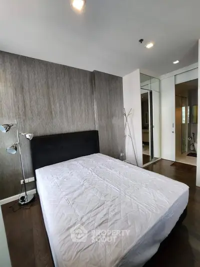 Modern bedroom with stylish decor and hardwood flooring in a contemporary apartment.