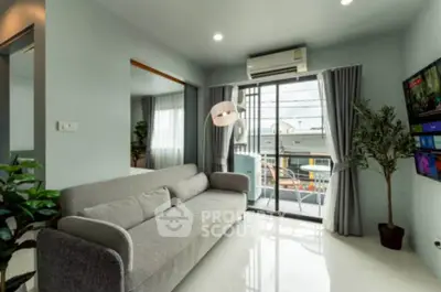 Modern living room with sleek gray sofa, large window, and balcony access, perfect for urban living.