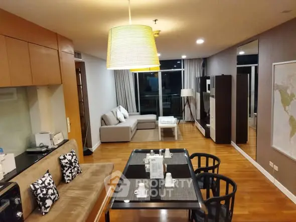 Spacious modern living room with stylish decor and dining area, featuring wooden flooring and ambient lighting.
