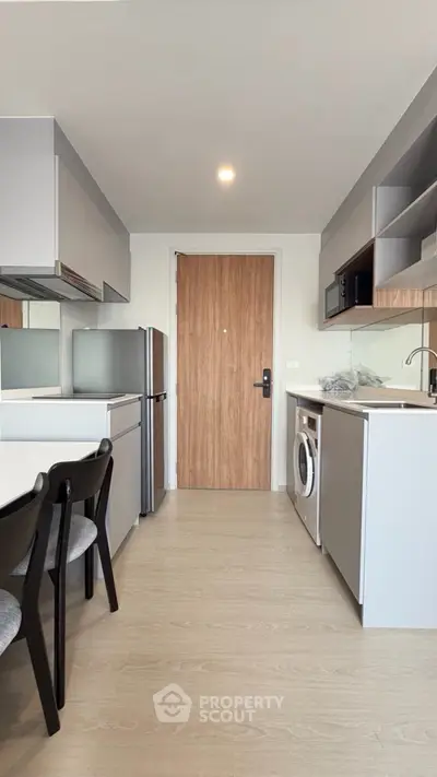 Modern kitchen with sleek cabinetry, integrated appliances, and a washing machine in a compact layout.