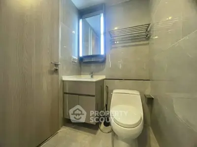 Modern bathroom with sleek fixtures and illuminated mirror in contemporary apartment.