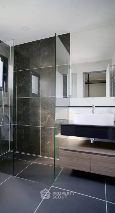 Modern bathroom with sleek glass shower and stylish vanity in luxury apartment.