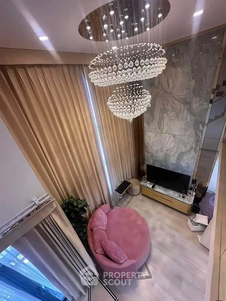 Luxurious living room with elegant chandelier and plush pink seating, perfect for modern comfort and style.