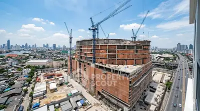High-rise building under construction with cranes and city skyline view