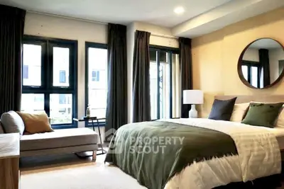 Spacious bedroom with modern decor and large windows offering natural light.