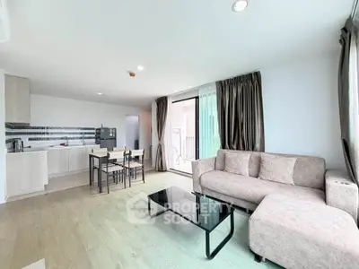 Spacious modern living room with open kitchen and balcony access, featuring stylish furniture and natural light.