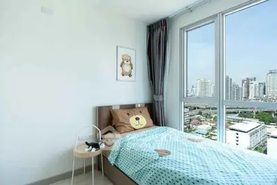 Cozy bedroom with city view, featuring a cute bear-themed decor and large windows.