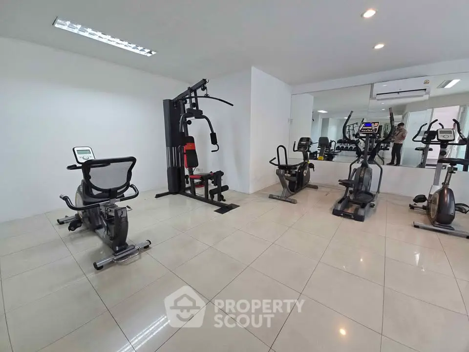Modern gym with exercise equipment in a spacious room with tiled flooring.