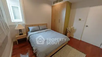 Cozy bedroom with wooden flooring and modern furnishings in a stylish apartment.