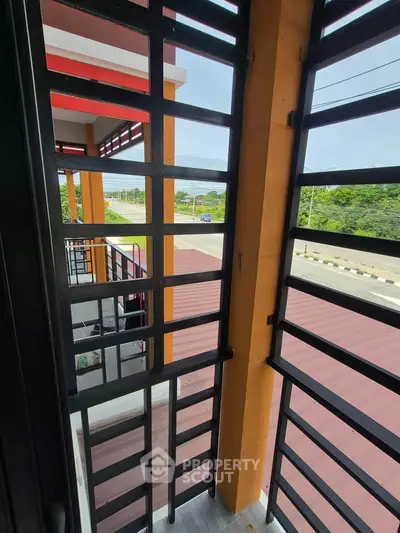 Modern balcony with metal railing offering a scenic view of the road and greenery.