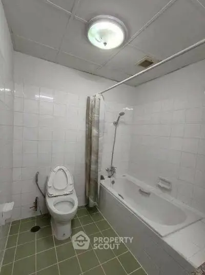 Spacious bathroom with bathtub and modern fixtures in a tiled setting.