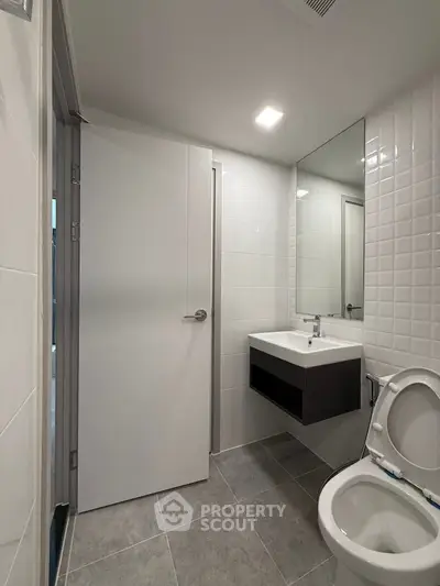 Modern bathroom with sleek fixtures and minimalist design, featuring a wall-mounted sink and contemporary tiling.