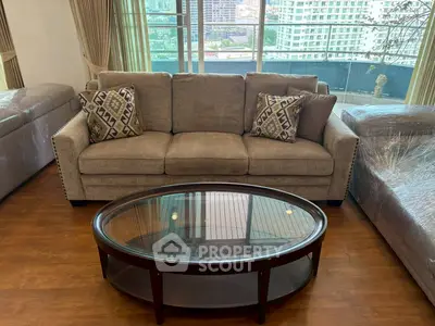 Spacious living room with elegant sofa and city view from large windows.