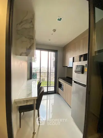 Modern kitchen with sleek cabinetry and balcony view, featuring built-in appliances and a stylish dining area.