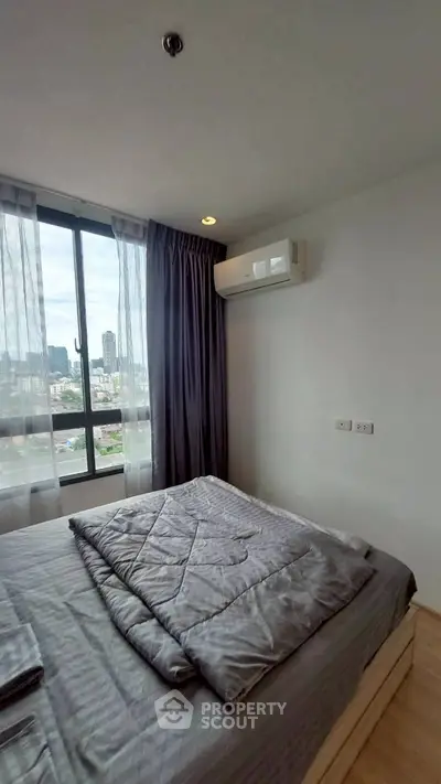 Modern bedroom with city view, featuring a cozy bed and air conditioning, perfect for urban living.