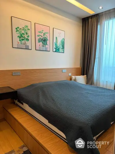 Cozy bedroom with a large comfortable bed, wooden headboard, and botanical artwork, complemented by warm lighting and elegant drapery.