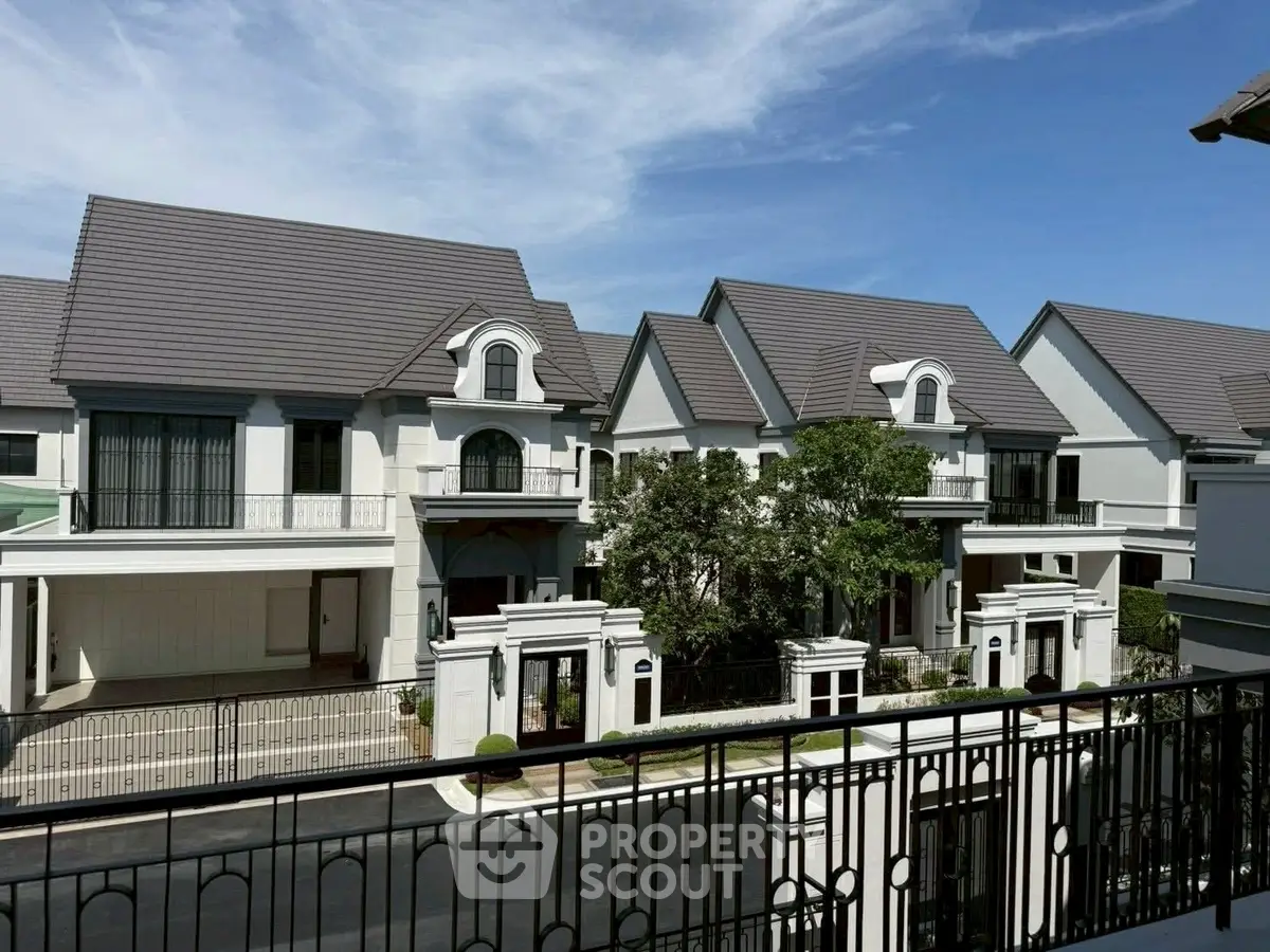 Luxurious suburban homes with elegant architecture and spacious balconies under a clear blue sky.