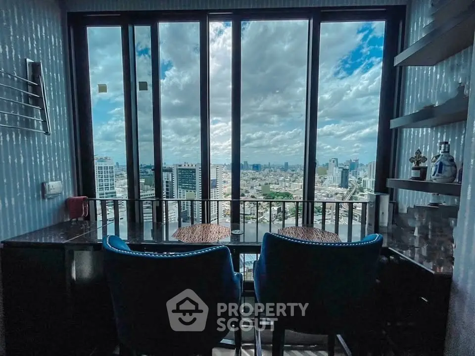 Stunning city view from a modern high-rise apartment with floor-to-ceiling windows and cozy seating area.