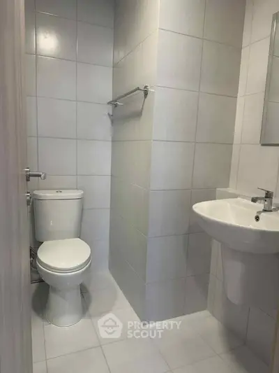 Modern minimalist bathroom with sleek white fixtures and tiled walls.