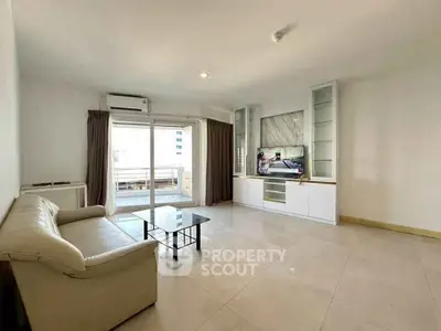 Spacious living room with modern decor and large windows leading to a balcony.