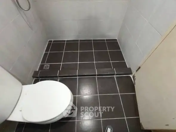 Compact bathroom with tiled floor and white toilet in a minimalist design.