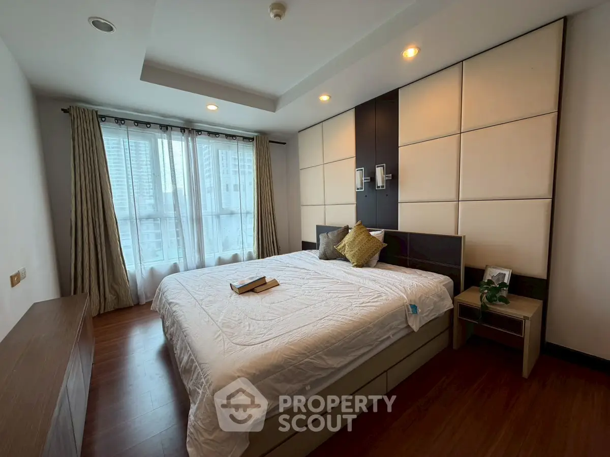 Spacious bedroom with modern decor and large window offering city views.