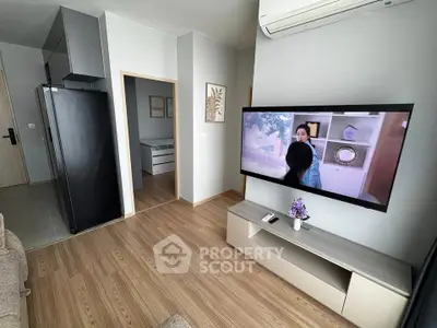 Modern living room with wall-mounted TV and sleek furniture in a cozy apartment.