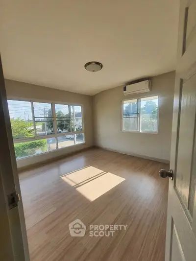 Bright empty bedroom with large windows and wooden flooring, perfect for natural light lovers.