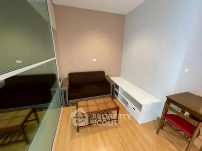 Cozy living room with modern furniture and wooden flooring in a compact apartment.