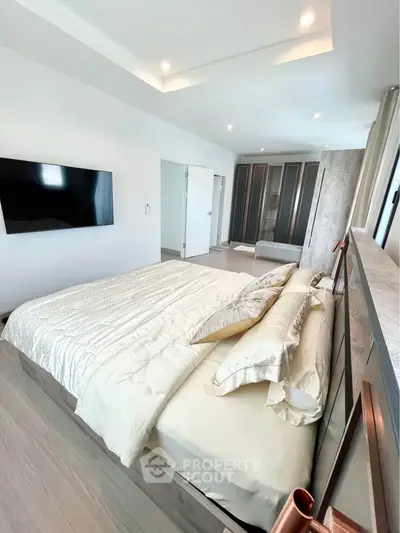 Luxurious bedroom with modern design and large TV, featuring elegant bedding and spacious wardrobe.