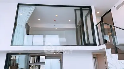 Modern duplex apartment with large windows and sleek staircase, offering a bright and spacious living environment.