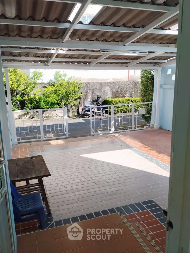 Charming covered patio with tiled flooring and street view, perfect for relaxation.