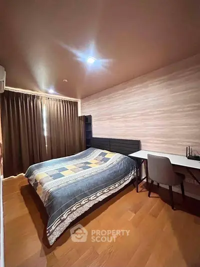 Cozy bedroom with wooden flooring, stylish bed, and study desk in modern apartment.