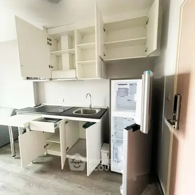 Modern kitchen with open cabinets and fridge in a compact apartment